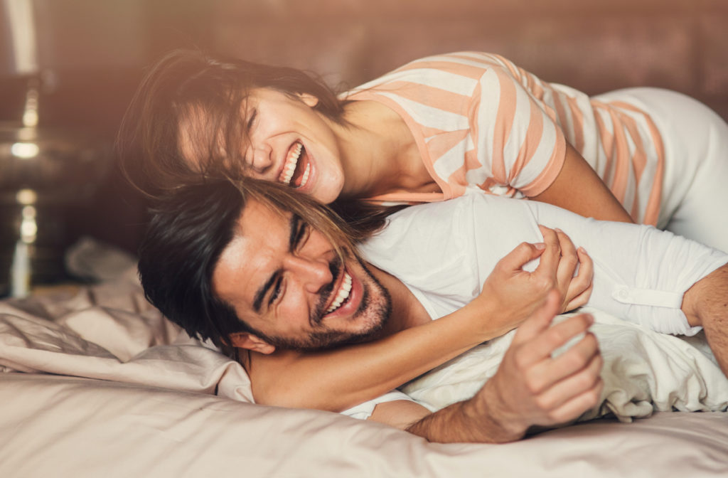 Happy young playful couple in bed.