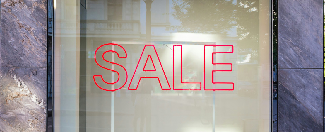 The word, "SALE" written in red on a glass window.