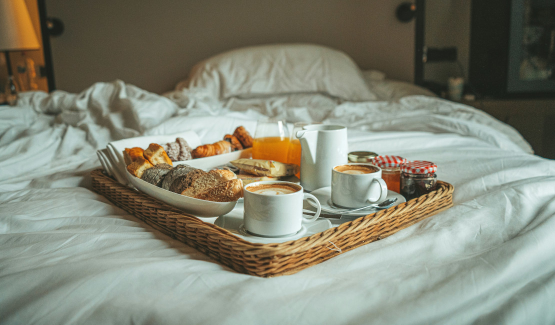 Breakfast tray on a white bed. Find beds for sale at The Mattress Warehouse