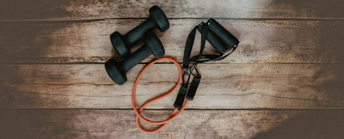 Black fitness dumbells and skipping rope against a wooden background